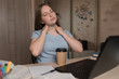 © byswat - Tired kneading neck, muscle pain, teenager girl 12-15 years old, rest after hard lesson, home laptop. E-education and distance learning Internet and video communications. A cup of coffee with tea.
