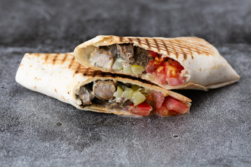 pork roll with tomato and pickled cucumbers. fried pita bread on a stone plate