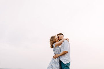 Young couple of man and woman standing and hugging in an open field, outdoors, on clean white background.