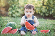 © Tamara Sales  - boy with watermelon sitting on grass in a backyard in overalls stock photo royalty free