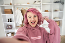 Excited Hipster Gen Z Teen Girl Fashion Social Media Channel Blogger Stylist With Pink Hair Piercing Wear Hoodie Look At Camera Record Vlog Video Tutorial In Front Of Clothes Wardrobe, Face Headshot.