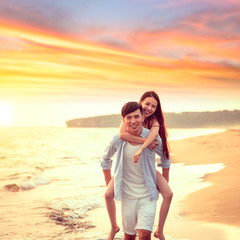 Wall Mural - happy young Man Giving Woman Piggyback On Summer Beach