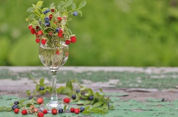 Poster - berries of wild strawberries and forest blueberries on a background of nature on an old rustic board. Country style. Soft focus. Space for text