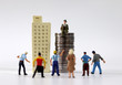 © Hyejin Kang - A variety of miniature people gathered in front of miniature buildings and piles of coins.