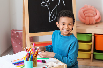 Wall Mural - Cute African-American boy drawing at school