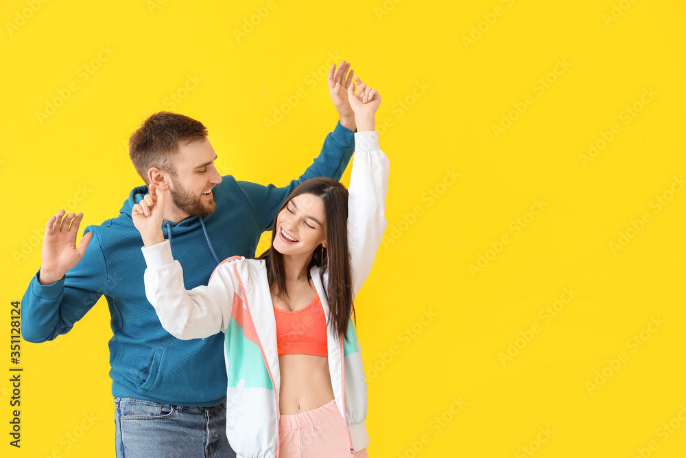 Happy young couple dancing against color background