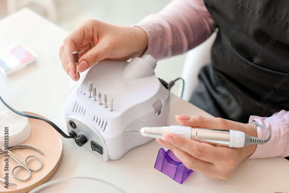 Manicure master working with modern milling cutter in beauty salon, closeup