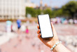 Person holding smartphone outdoors in the city, phone mockup with empty white screen.