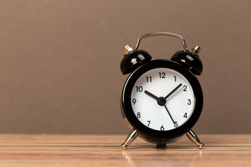 Wall Mural - Black retro alarm clock with bells on a wooden table, daily routine concept.