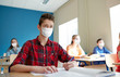 © Syda Productions - education, healthcare and pandemic concept - group of students wearing face protective medical mask for protection from virus disease with books at school lesson
