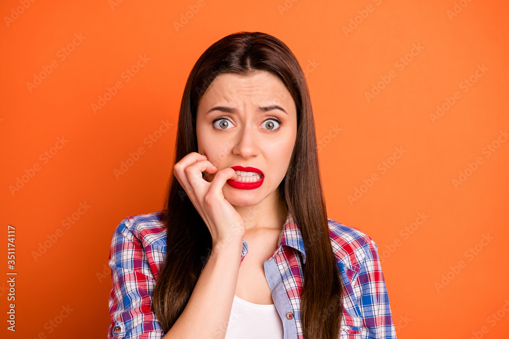 Close-up portrait of her she nice attractive nervous worried straight-haired girl wearing checked shirt having panic attack biting nails isolated on bright vivid shine vibrant orange color background - obrazy, fototapety, plakaty 