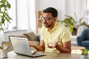 Sticker - remote job, technology and people concept - sad young indian man in glasses with laptop computer working at home office