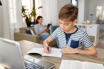 Wall Mural - children, education and learning concept - student boy with book writing to notebook at home