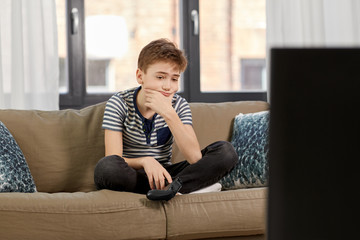 Wall Mural - leisure, technology and children concept - sad boy with gamepad playing video game at home