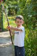 Chłopiec bawi się latem w ogródku drewnianym łukiem