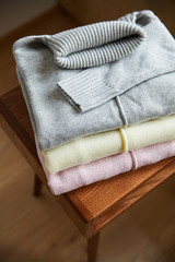 Wall Mural - close up view of pink, beige and grey knitted soft sweaters on wooden table in room