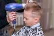 © ARVD73 - Hair dressing by the hair dryer. Hairdresser does a hair to the caucasian boy in hairdressing salon.
