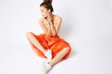 An Asian Model Girl Posing In Red Dress And White Sneakers In Studio On A White Background Lightly With Emotion