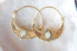 Brass pair of earrings in oriental style on white shell background