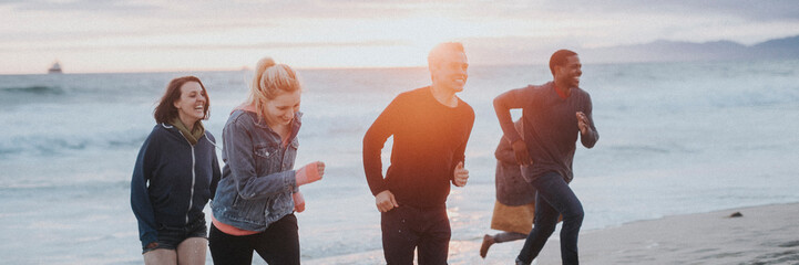 Wall Mural - Cheerful friends running on the beach