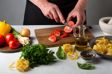 Wall Mural - Preparing pasta men hands slicing tomato