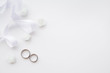 Wedding rings are decorated with a ribbon and white flowers with copy space. Concept backgrounds for weddings.