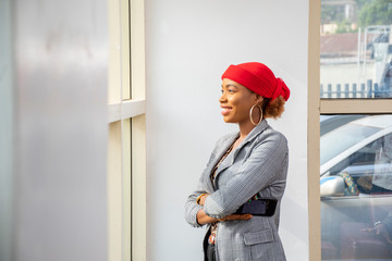 young african business woman wearing a suit smiling and looking out the window in her office