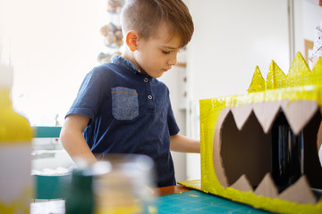 Wall Mural - Boy painting a cardboard dinosaur costume