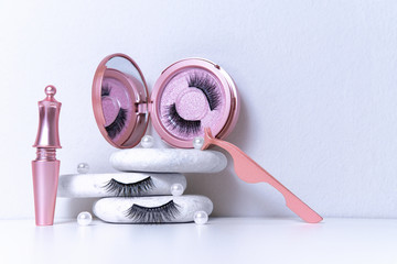 Wall Mural - Magnetic fake artificial eyelashes in pink mirror kit, eye liner, tweezers on white background. Home eyelash extension, cosmetology tool concept, beauty treatment, improving physical appearance