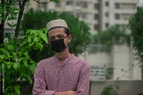 Cuadros en Lienzo Muslim boy with traditional punjabi wears protective mask and celebrating ramada