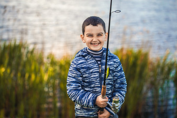 Cute boy catches fish on a summer lake. Activity in nature fishing. Happy childhood