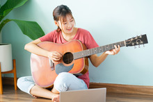 Young Asian Woman Learning Guitar At Home
