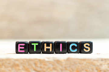 Poster - Black bead with color letter in word ethics on wood background