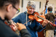 © Hill Street Studios - Smiling teacher teaching student to play violin in classroom