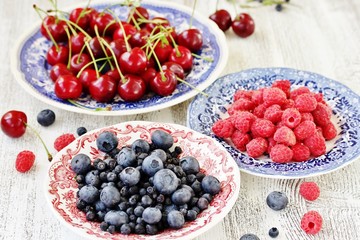 Canvas Print - Red and blue berries - forest blueberries, blueberries, raspberries, cherries in a  dish with a red and blue pattern.  Summer berries. Soft focus