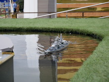 A Radio-controlled Model Of A Warship With Naval Guns Floats In An Artificial Reservoir, Similar To A Port On The Street On A Warm Summer Day.