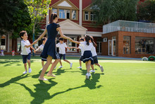 Teacher And Students Playing In Kindergarten Playground
