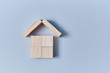 Wooden cubes under house roof of wooden planks, copy space. Mockup style for creative design. Isolated on blue backdrop