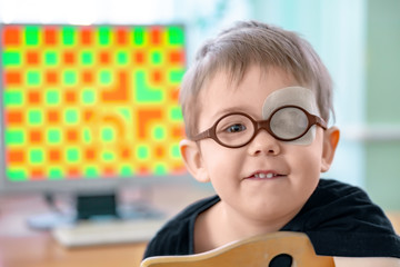 A little boy wearing glasses and an eye patch (plaster, occluder). He undergoes vision treatment to prevent amblyopia and strabismus (squint, lazy eye). Child congenital vision disease problem.