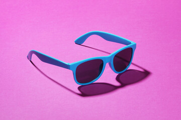 Blue sunglasses on a pink background with shadow