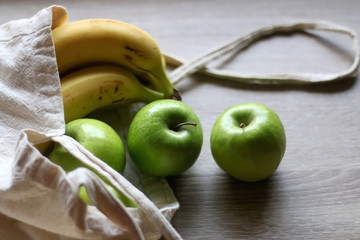 Canvas tote bag with apples and bananas. Selective focus.