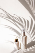 Cosmetic Tonic And Serum In Blank Packages On A Background Of White Wall With Palm Leaves Shadows. Natural Skincare Products Concept.