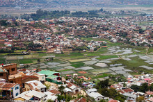An Aerial View Shows The Flooded Rice Paddies Of Antananarivo, Madagascar Sandwiched Between Densely Crowded And Run Down Housing Neighborhoods.