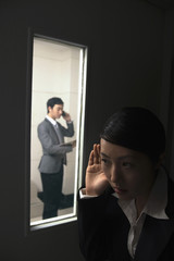 Businesswoman eavesdropping on businessman talking on the phone