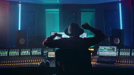Fototapete - Artist, Musician, Audio Engineer, Producer in Music Record Studio, Uses Control Desk with Computer Screen showing Software UI with Song Playing. Celebrates Success with Raised Hands, Dances. Back View