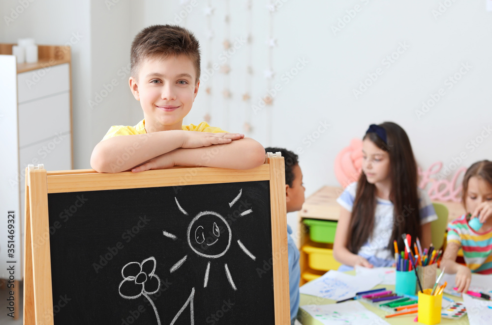 Cute boy drawing at school