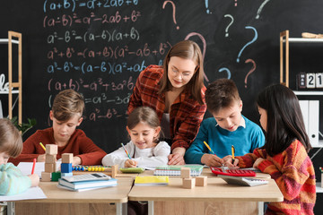 Children with math teacher during lesson in classroom