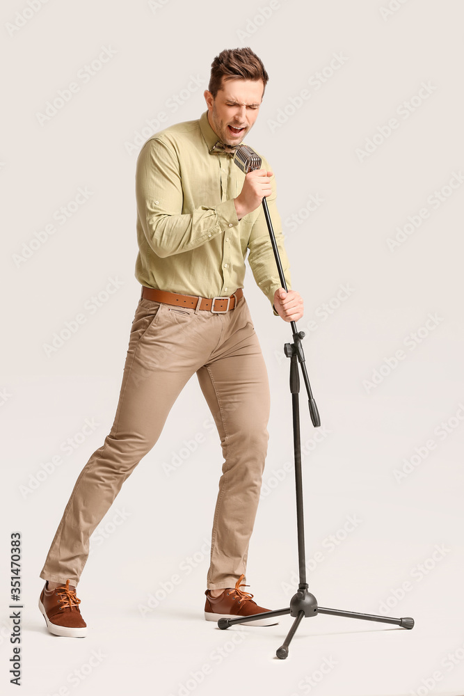 Young man singing on light background