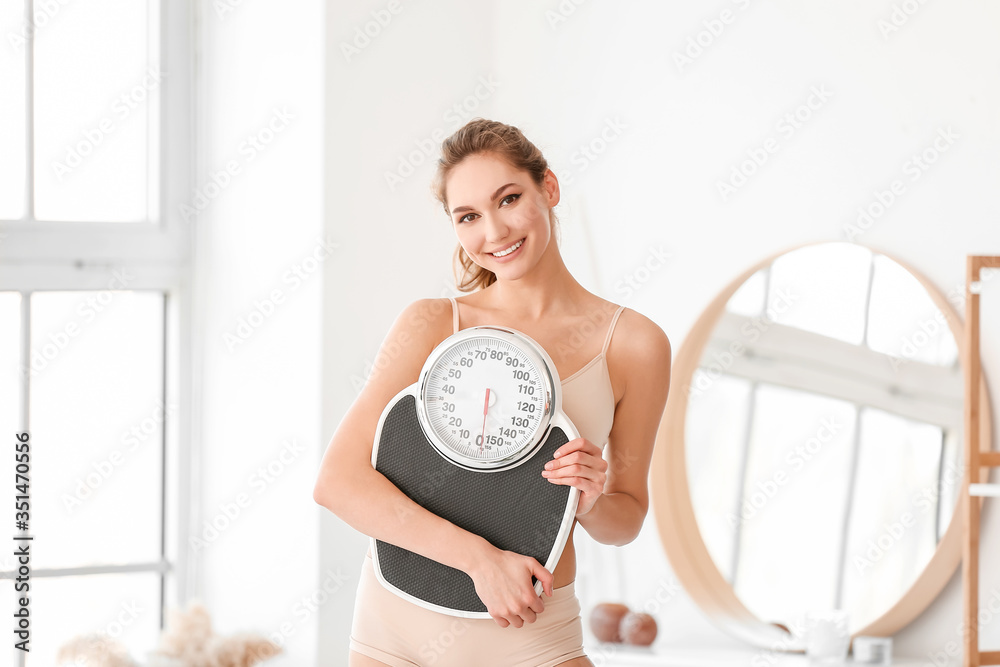Young woman with weight scales at home