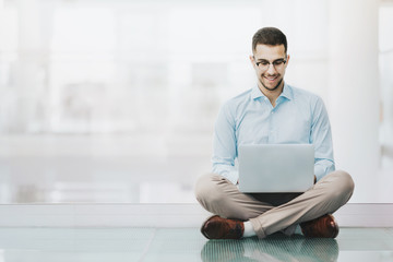 Elegant, young man waiting for a job interview, preparing information on a laptop